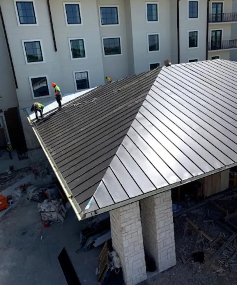 Crew installing standing seam metal roof panels on a commercial project in Garfield
